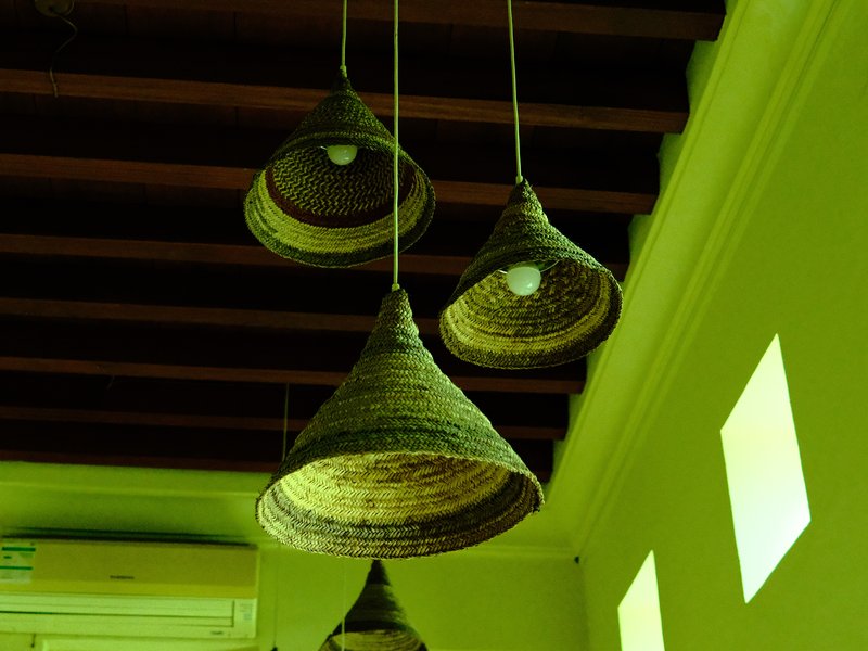 Four woven pendant lamps hanging from a ceiling with a greenish hue.
