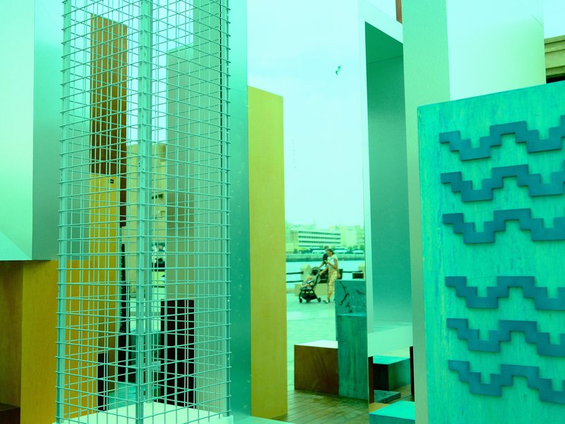 Abstract architectural installation with geometric shapes in teal and gold tones.