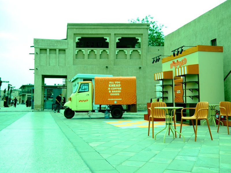 A vibrant food truck and kiosk in an urban setting with orange accents and modern seating.