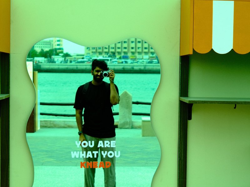 A person taking a selfie in a mirror with a colorful background and text overlay.