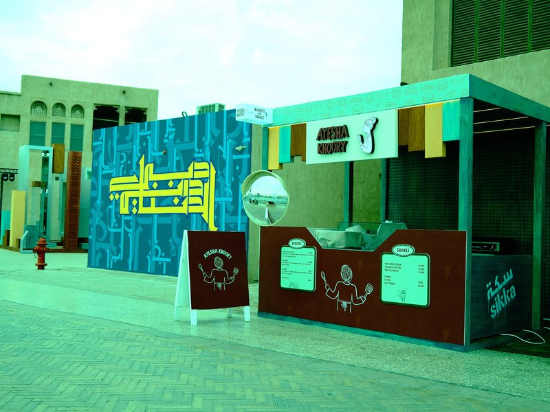 A colorful outdoor market stall with a vibrant backdrop and signage.