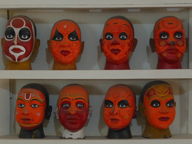 A display of colorful painted masks arranged in two rows, showcasing various facial designs and expressions.