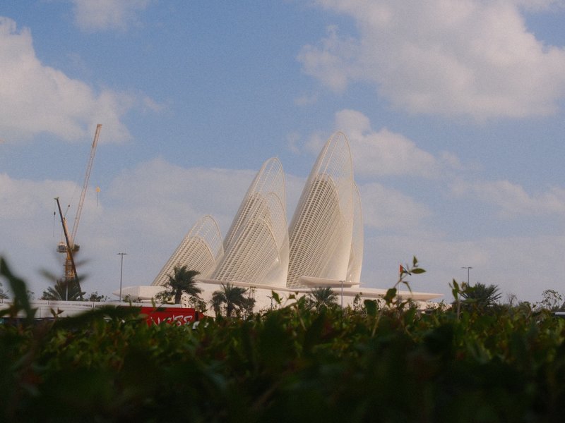 Three large white sail-like structures against a blue sky with scattered clouds.