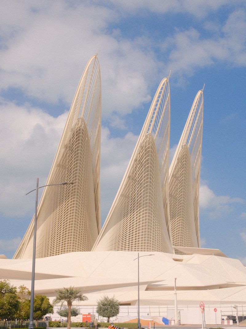 Three tall, sculptural structures with a light, airy design against a partly cloudy sky.