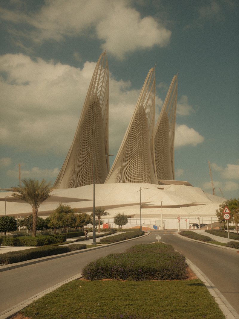 A modern architectural structure with tall, sweeping spires against a cloudy sky.