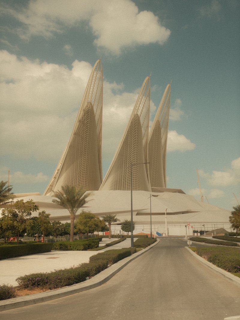 A modern architectural structure with tall, pointed features against a cloudy sky.