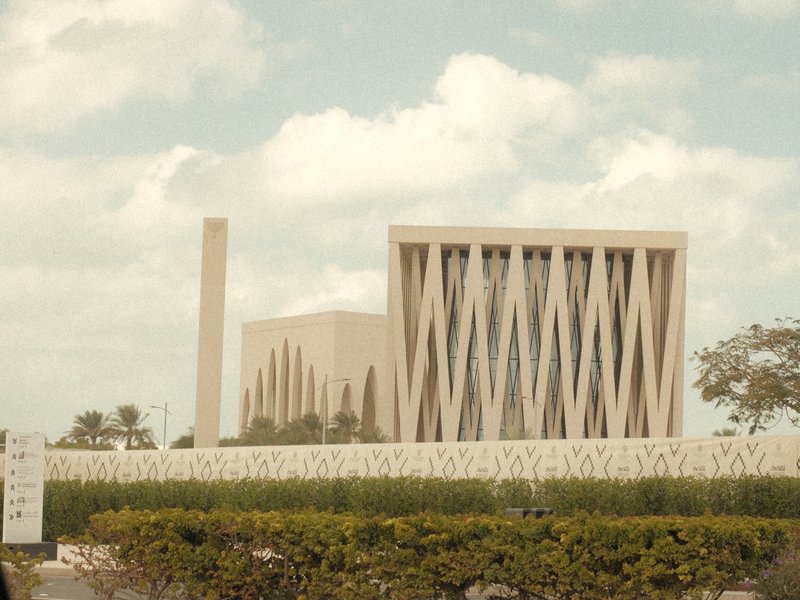 Modern architectural building with unique design, surrounded by greenery and blue sky.
