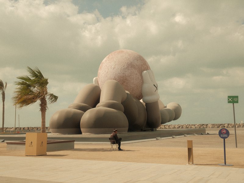 A large octopus sculpture on a coastal promenade with palm trees and cloudy skies.
