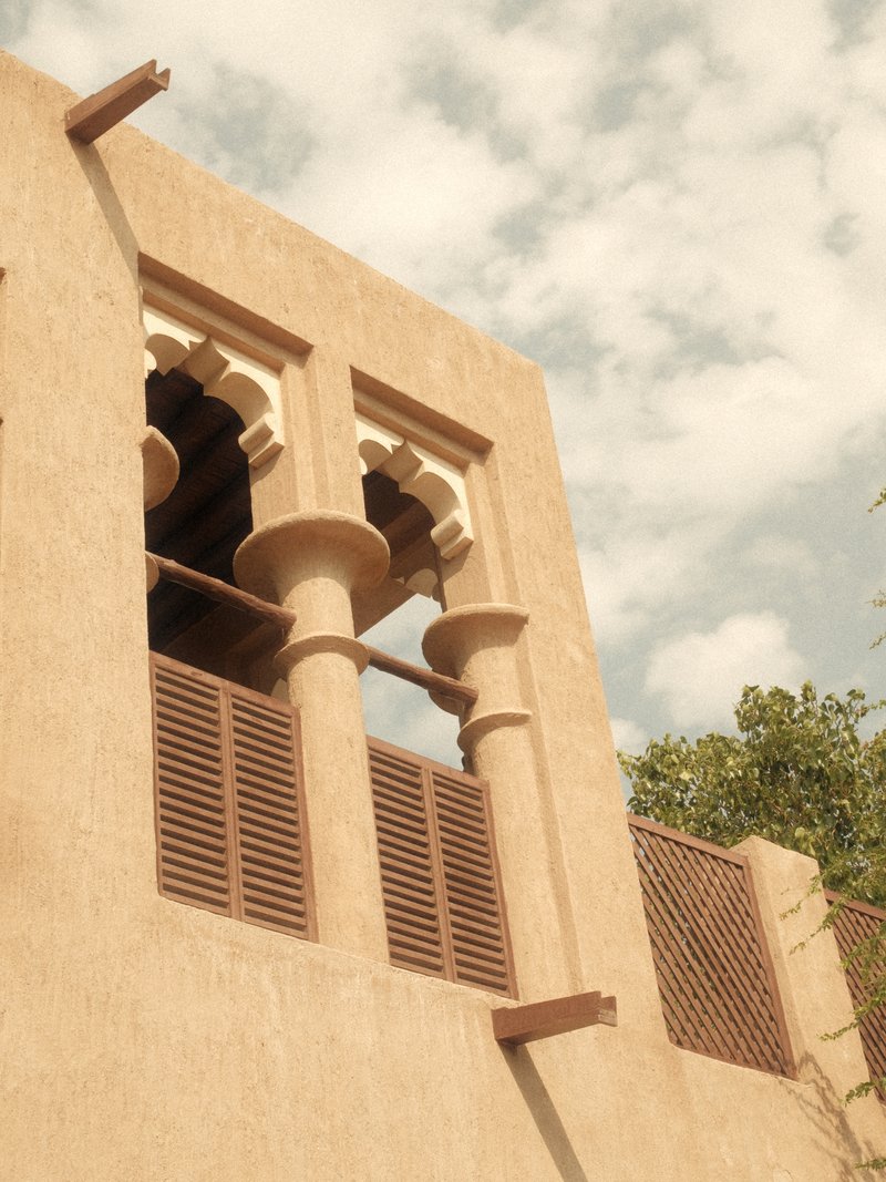 Close-up of an architectural building with arched windows and decorative columns against a cloudy sky.