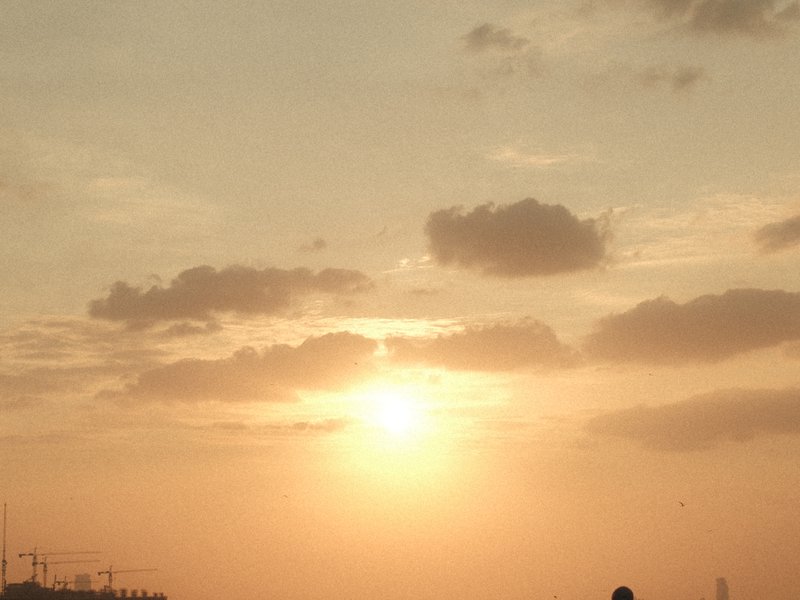 Silhouetted figure against a sunset with soft clouds and warm hues in the sky.
