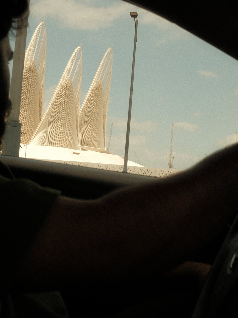 A view of a modern architectural structure with pointed white features, seen from inside a car.