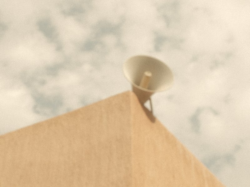 A megaphone mounted on the corner of a beige building against a cloudy sky.