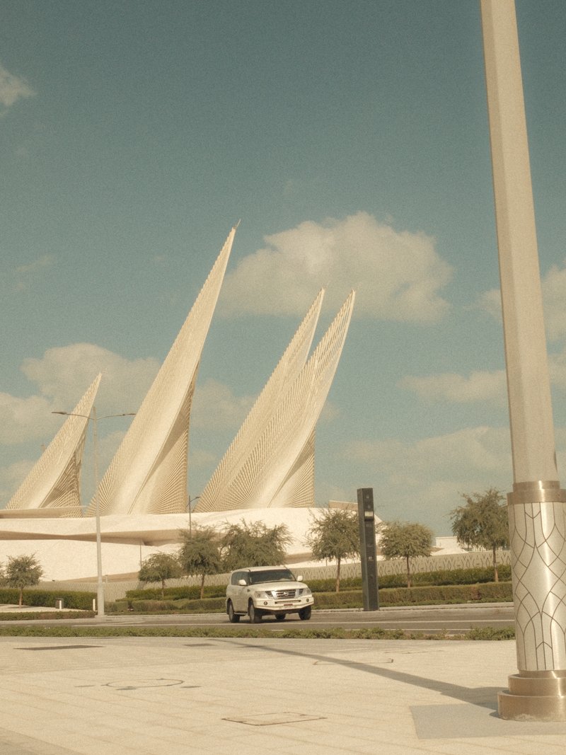A modern architectural structure with sharp, pointed features under a blue sky with fluffy clouds.
