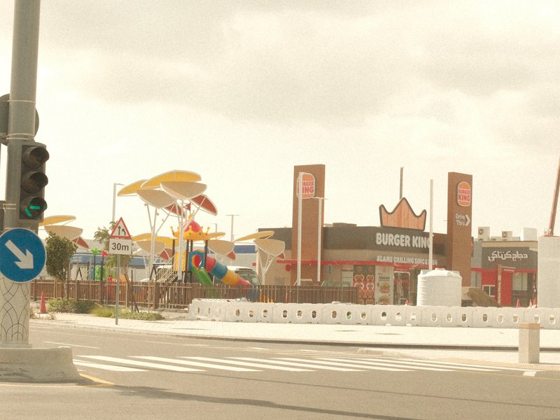 A colorful amusement park with large structures and signage, seen from a street corner.