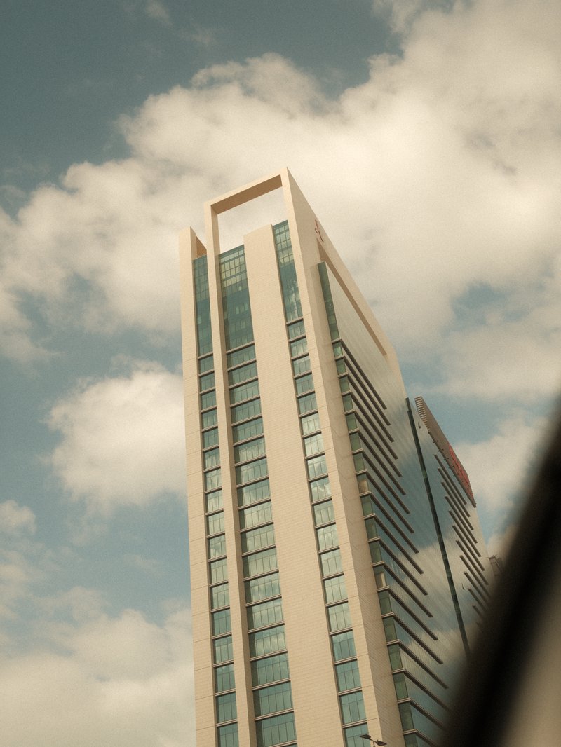 Tall modern building with glass windows under a cloudy sky.