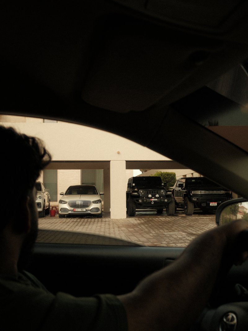 A person driving past a garage with multiple cars parked inside, viewed from inside a vehicle.