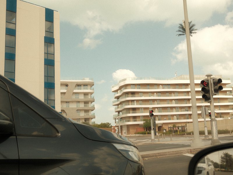 View of modern buildings and traffic lights from a car window on a sunny day.