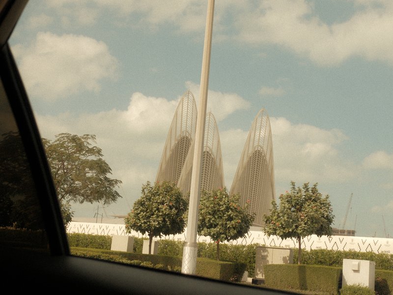 View of modern architectural structures with trees and a cloudy sky in the background.