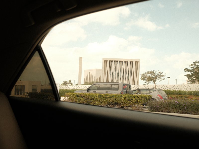 View from a car window showing a building and a cloudy sky.