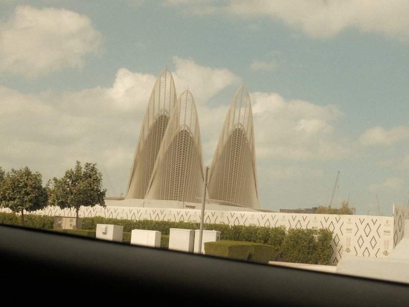 A modern architectural structure with tall, pointed features against a cloudy sky.