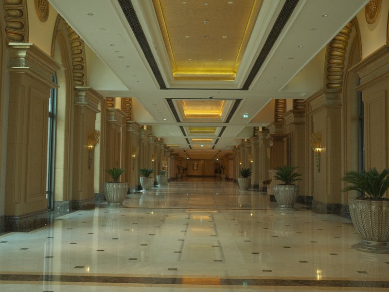A long, elegant hallway with marble flooring and decorative arches, illuminated by soft lighting.