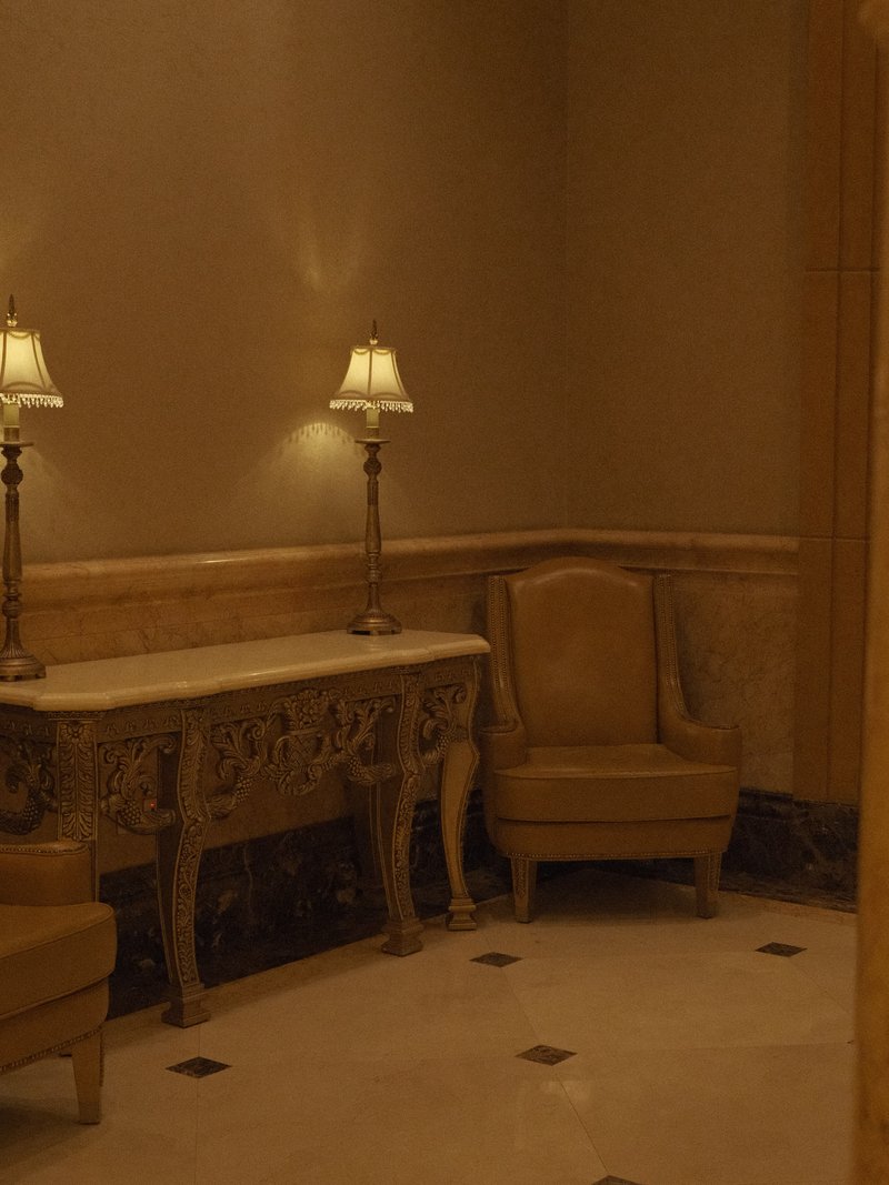 Elegant indoor corner with two lamps, a console table, and a chair in warm tones.