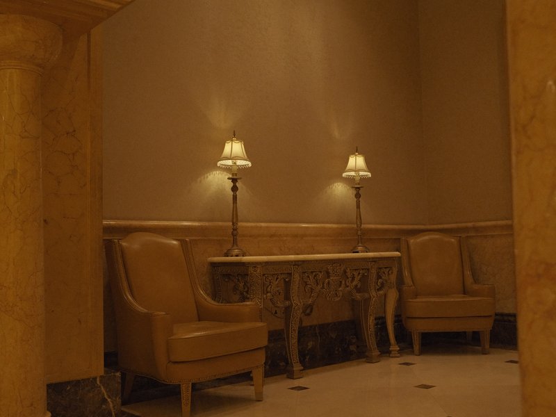 A cozy indoor setting with two leather chairs and a decorative console table illuminated by lamps.