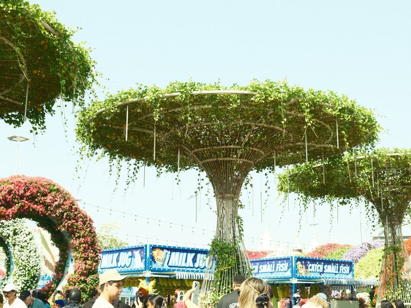 A vibrant outdoor scene featuring large, tree-like structures covered in greenery with people below.