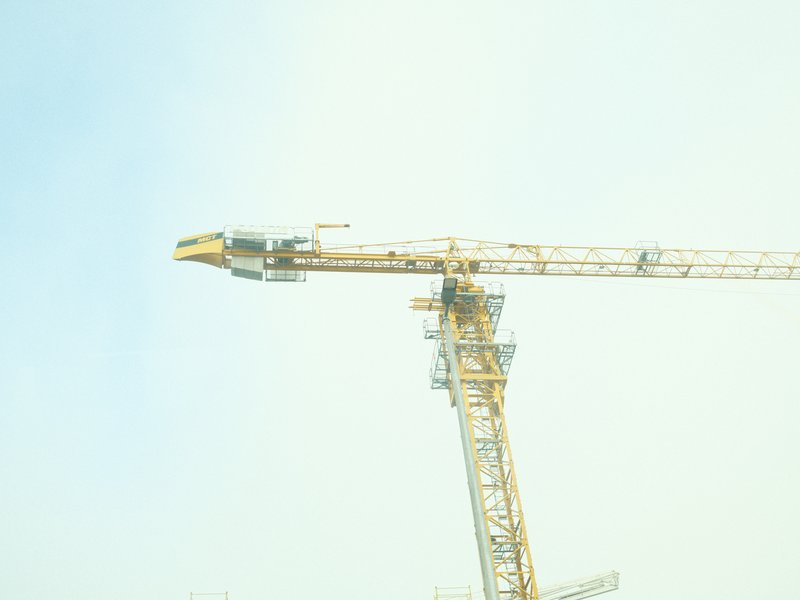 A close-up view of a construction crane against a pale sky.