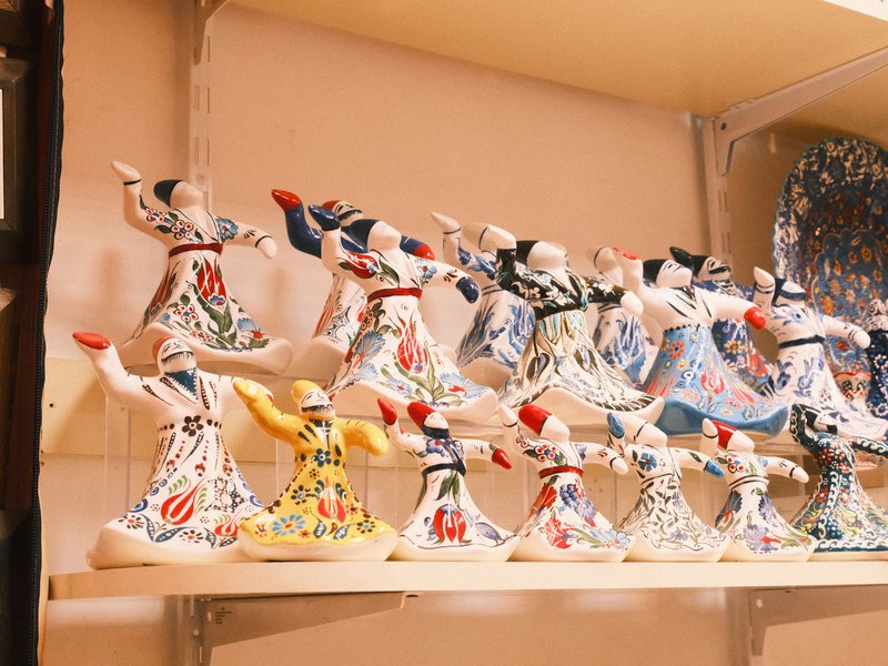 Colorful ceramic figurines of dancers displayed on a shelf, showcasing intricate patterns and designs.
