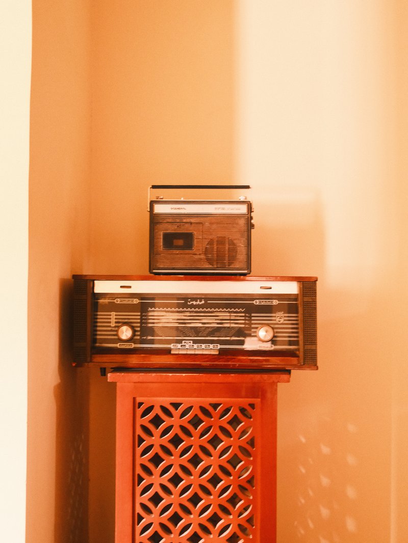 A vintage radio set placed on a wooden stand with intricate patterns, illuminated by soft light.