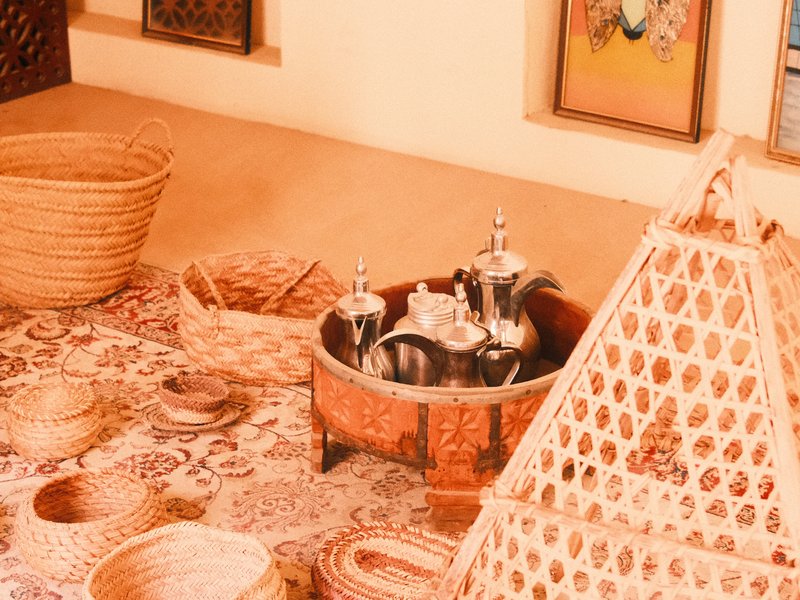 A cozy indoor scene featuring traditional woven baskets and a decorative tea set on a patterned rug.