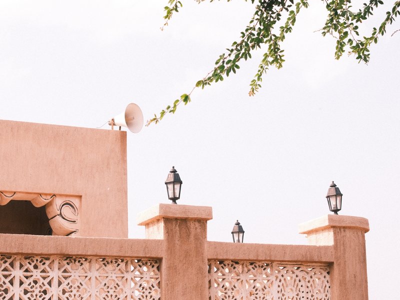 A close-up of a traditional building with decorative walls and lanterns under a clear sky.
