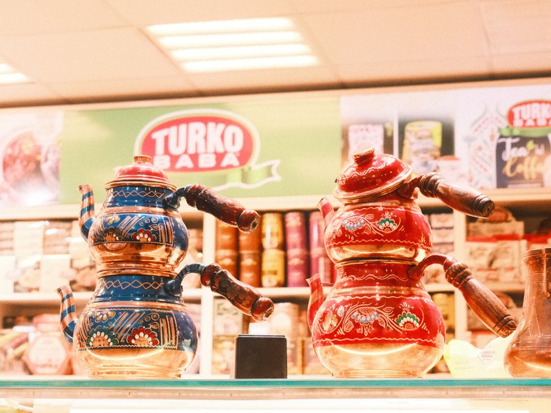 Two decorative teapots, one blue and one red, displayed on a shelf in a store.
