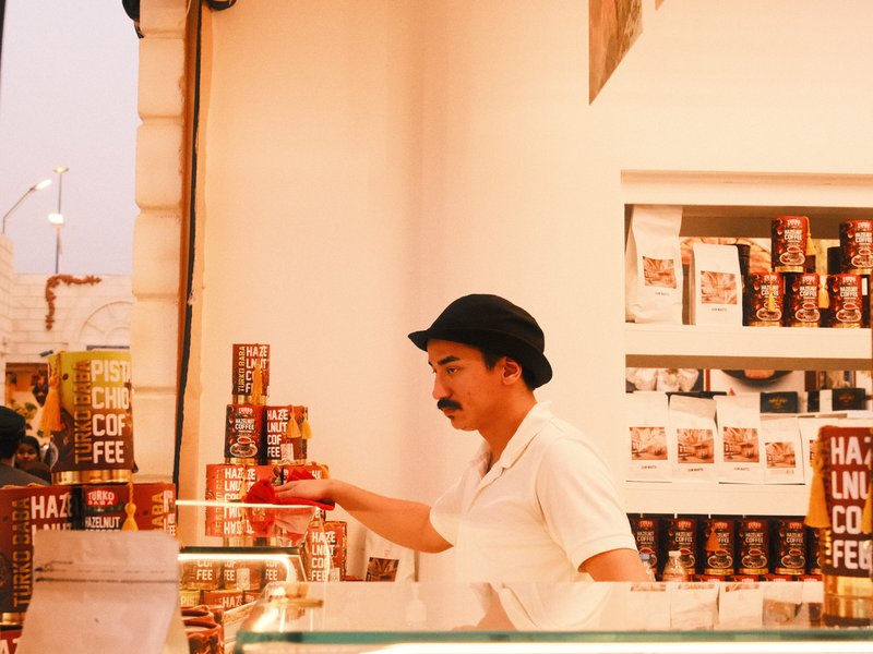A man in a hat examines a can in a bright store filled with coffee products.
