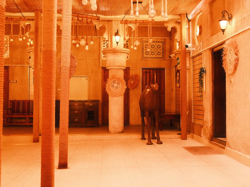 A warm-toned interior of a traditional building with wooden pillars and a horse standing in the center.