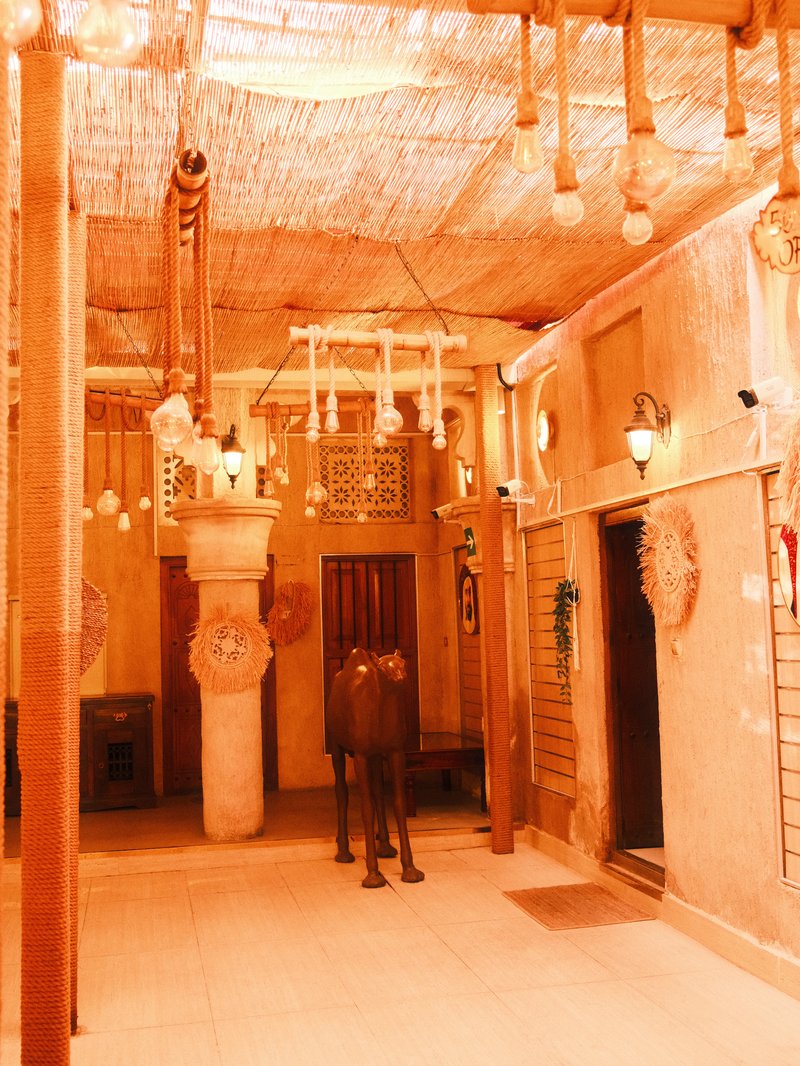 Interior of a traditional building with a horse statue, decorative lights, and rustic architecture.