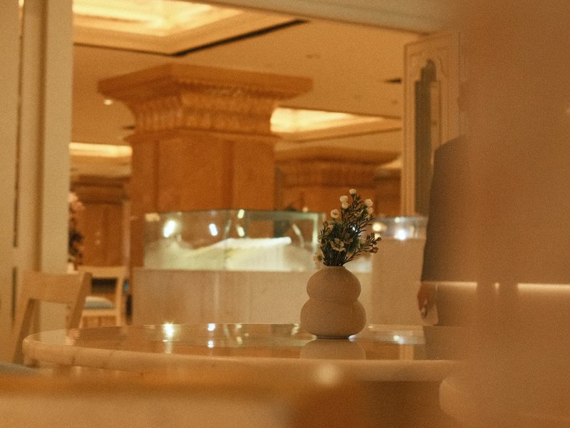 A softly lit interior scene featuring a vase on a table with blurred background elements.