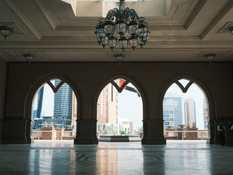 Interior view of an ornate room with arched windows showcasing a city skyline.