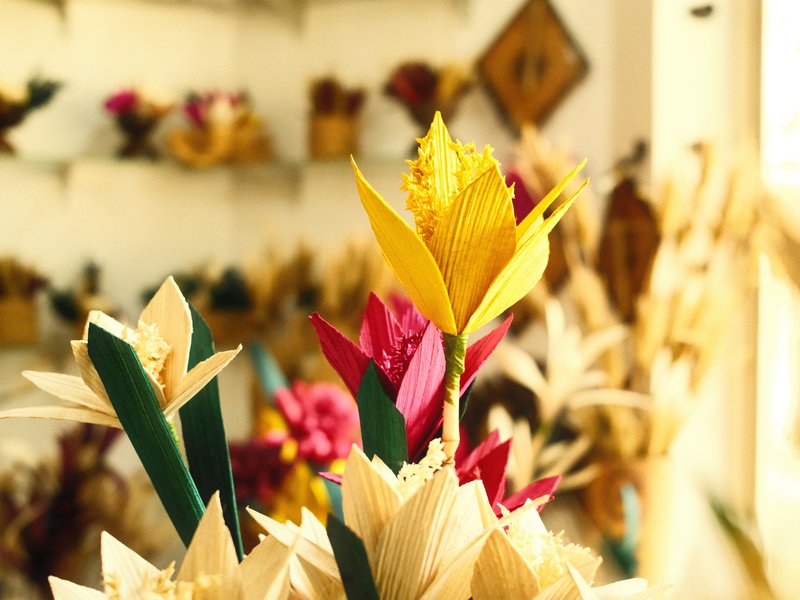 Colorful paper flowers in a bright indoor setting with a blurred background of more flowers.