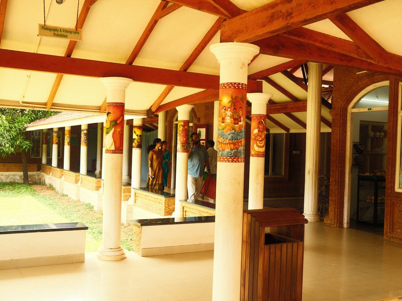 Interior view of a building with wooden beams, decorative columns, and people in the background.