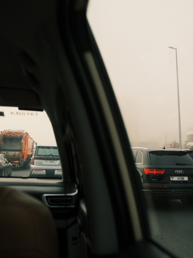 View from a car window showing traffic jam with blurred vehicles in a foggy atmosphere.
