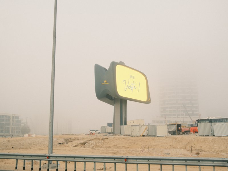A foggy scene featuring a large, illuminated billboard partially obscured by mist.