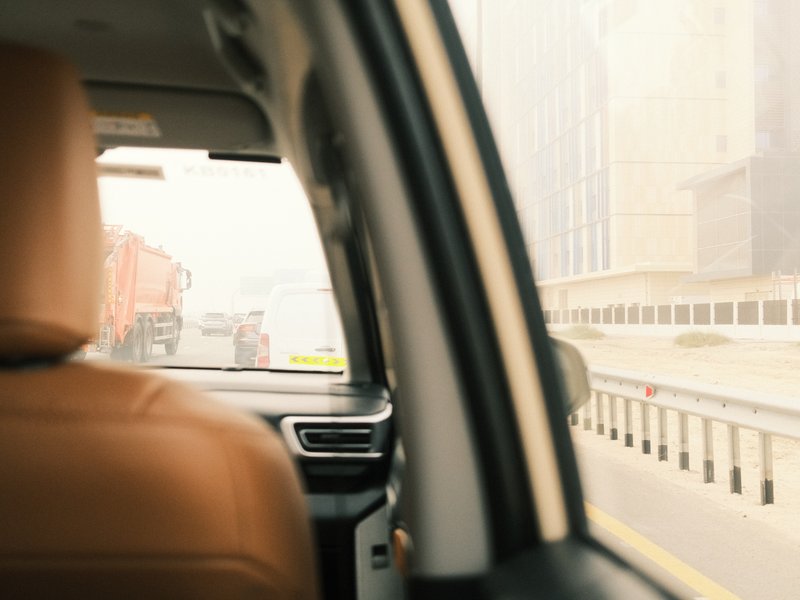 Interior view of a car with a focus on the driver's seat and a blurred cityscape outside.