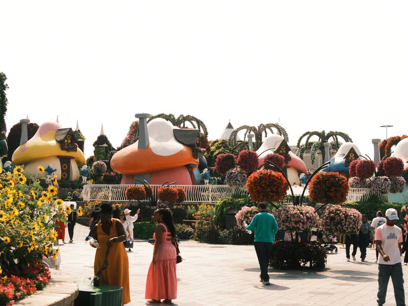Colorful mushroom-shaped structures in a vibrant garden with people walking around.