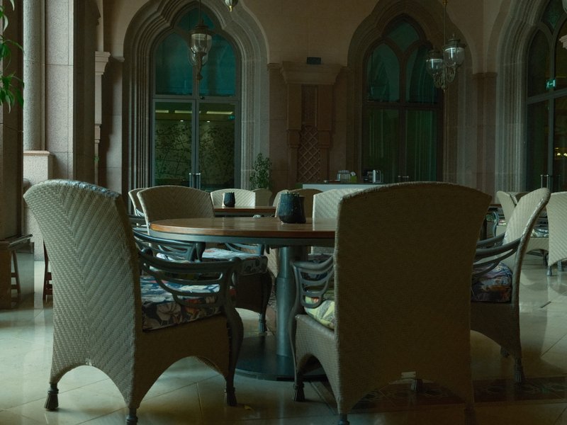 A cozy indoor seating area with elegant chairs and a round table, surrounded by arched windows.