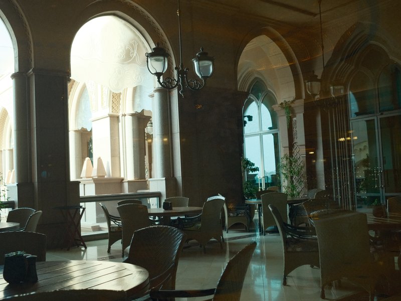 Interior of a stylish café with arched windows and elegant furniture, reflecting light.