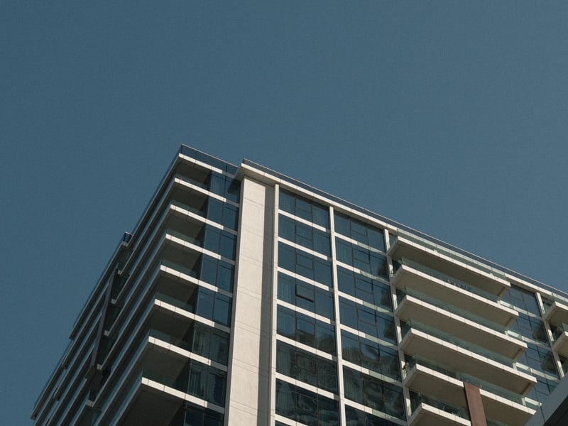 A modern glass building against a clear blue sky, showcasing architectural lines and reflections.