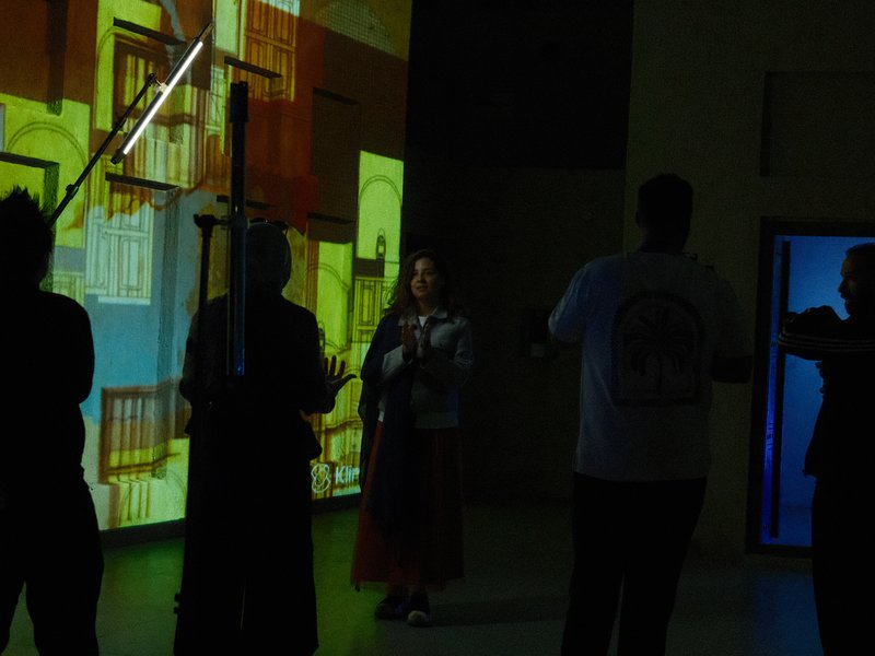Silhouetted figures in front of a colorful projection, creating a dynamic artistic scene.