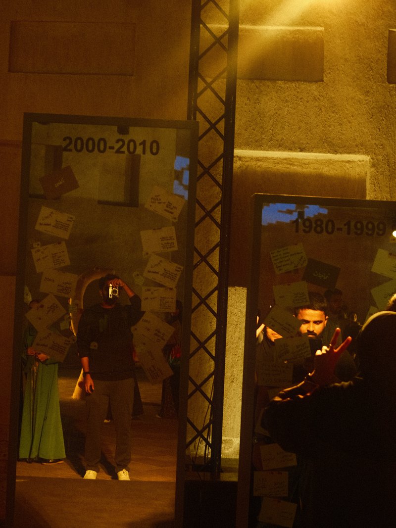 A person taking a selfie in a dimly lit space with mirrors displaying years and notes.